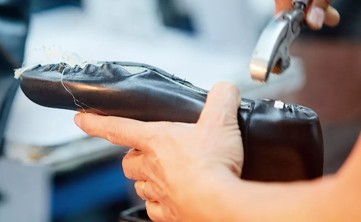 A shoe cobbler holds the sole of a leather shoe