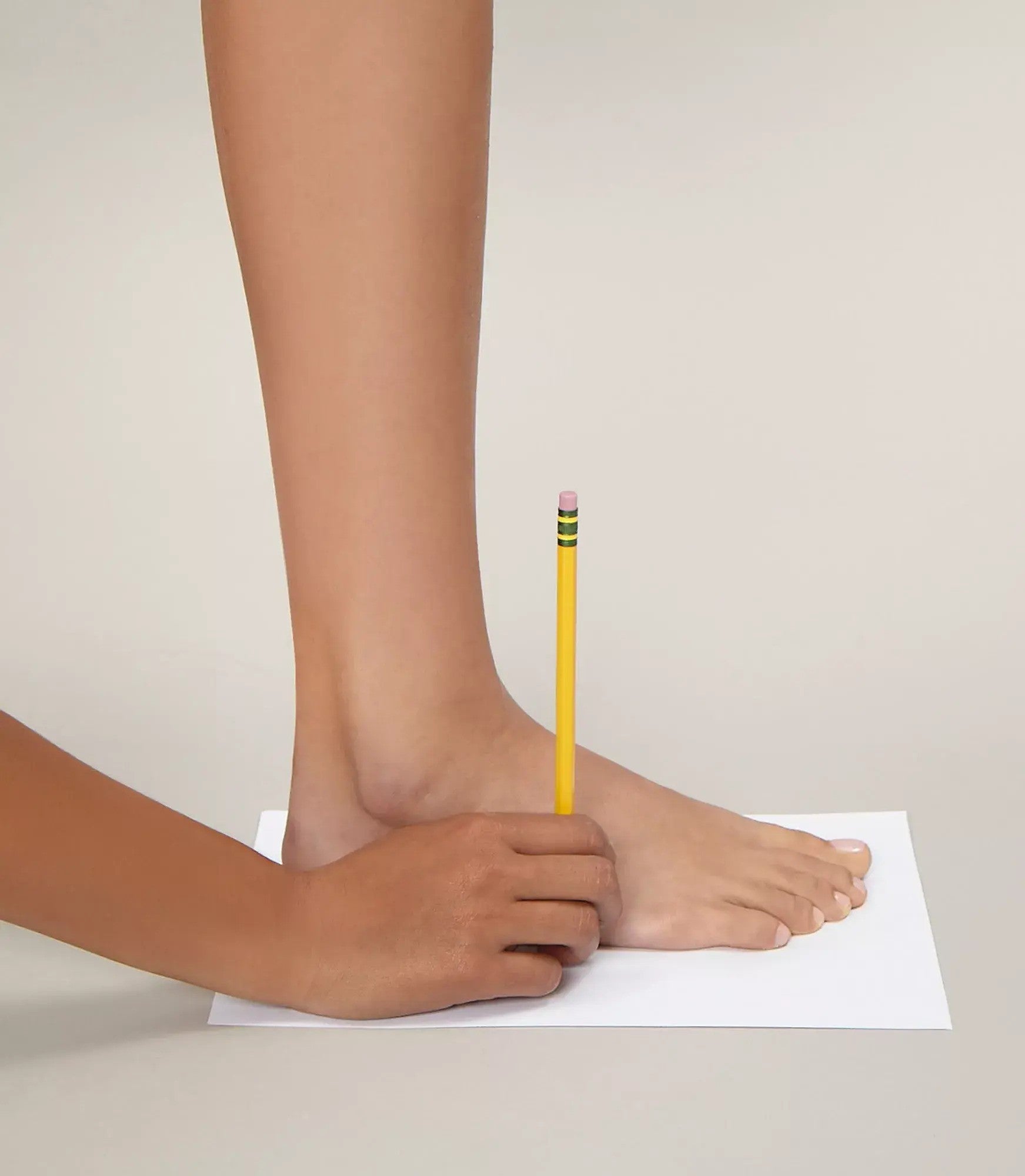 A caucasian individual wraps a measuring tape around their calf 