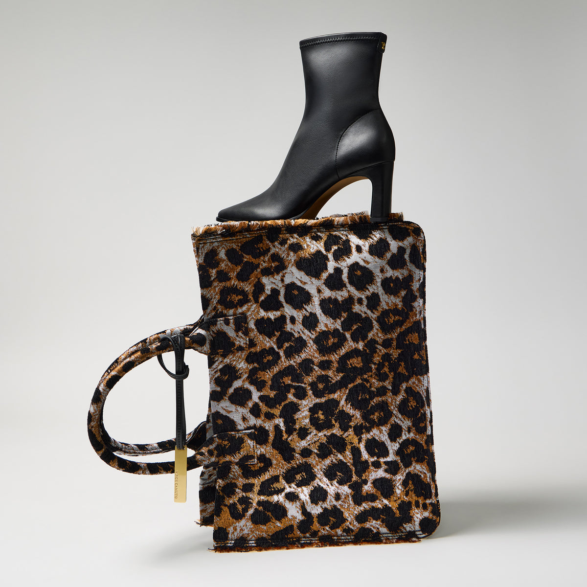 animal print tote bag and black bootie stacked against a gray background