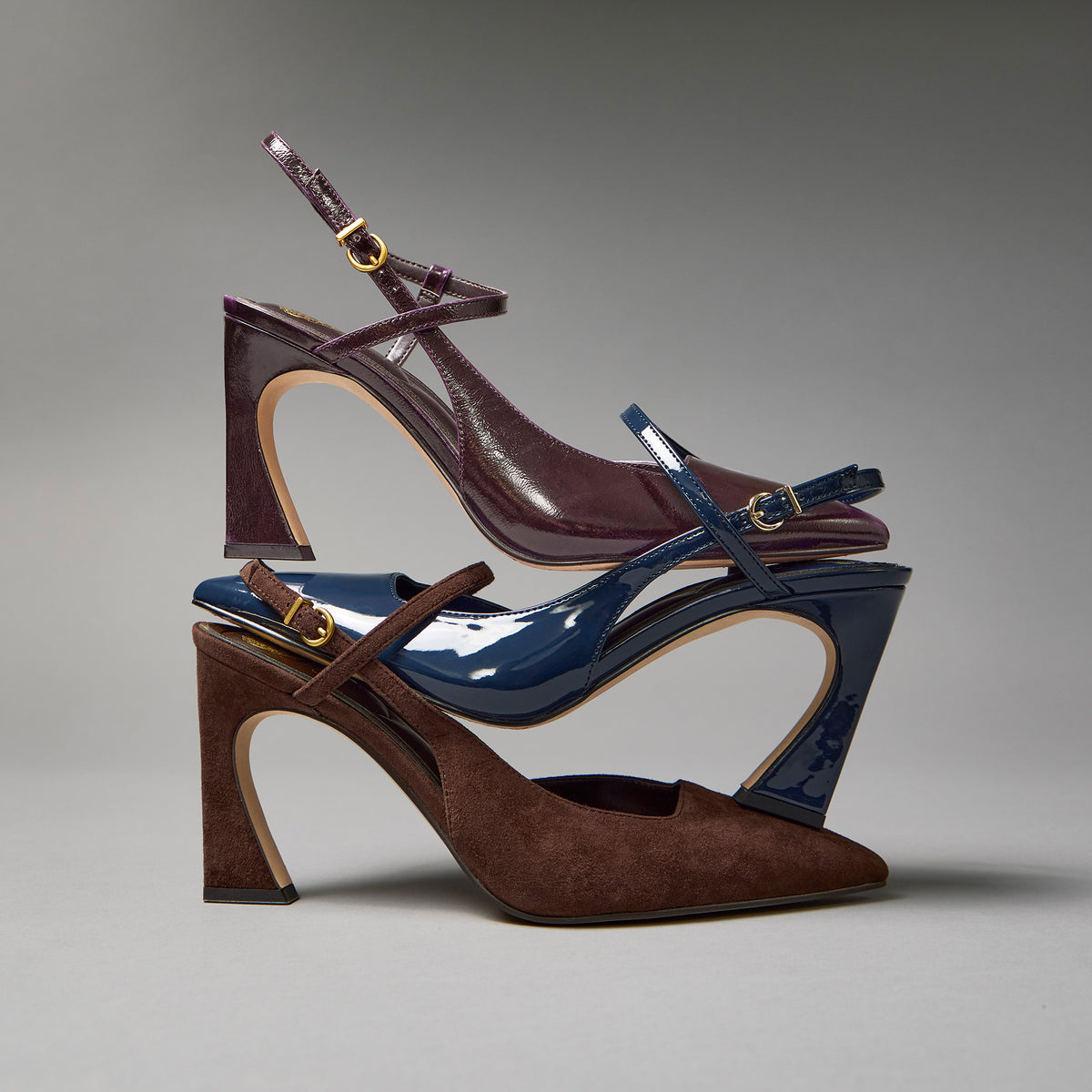 three fall colored high heels stacked against a gray background