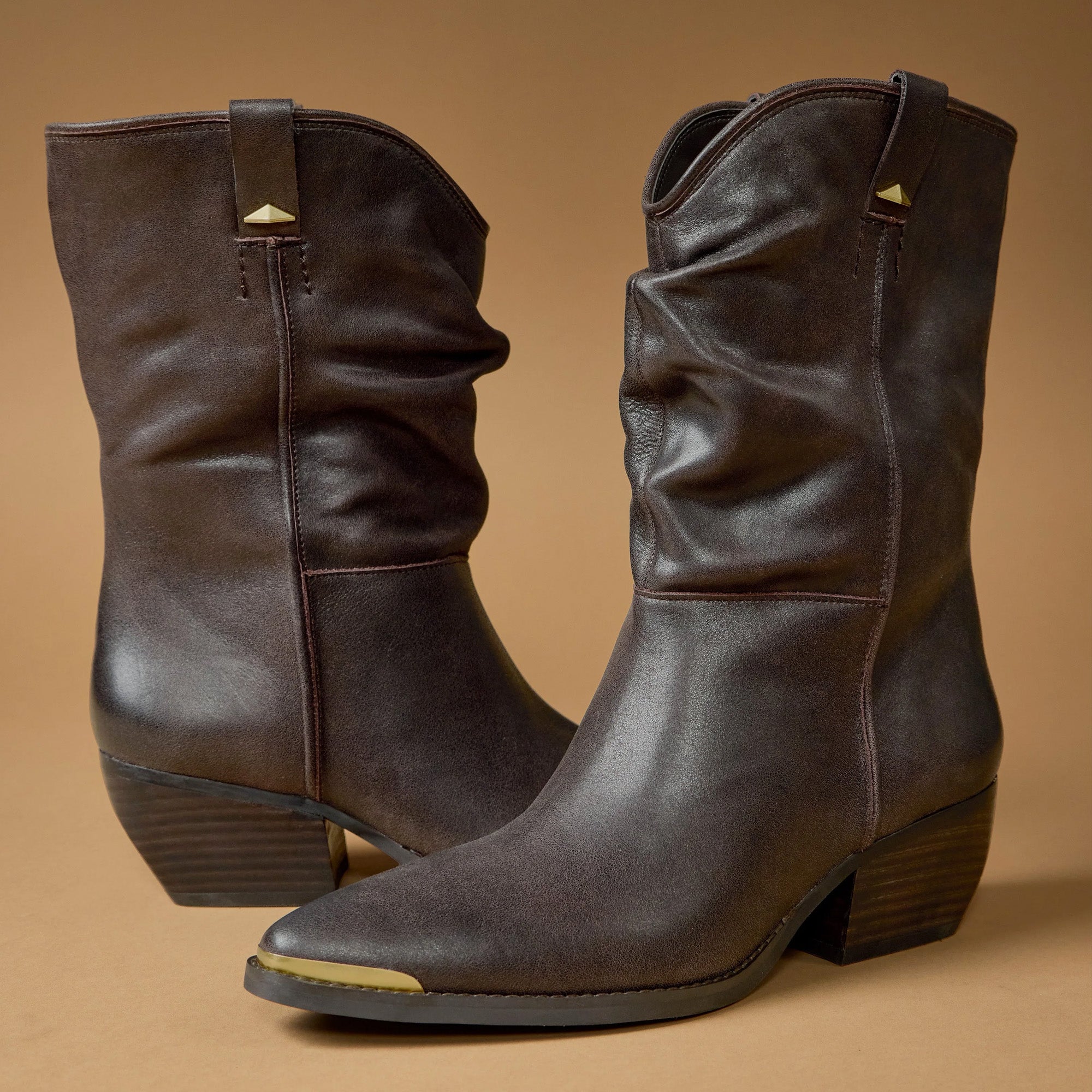 Brown, gold tipped boots on tan background
