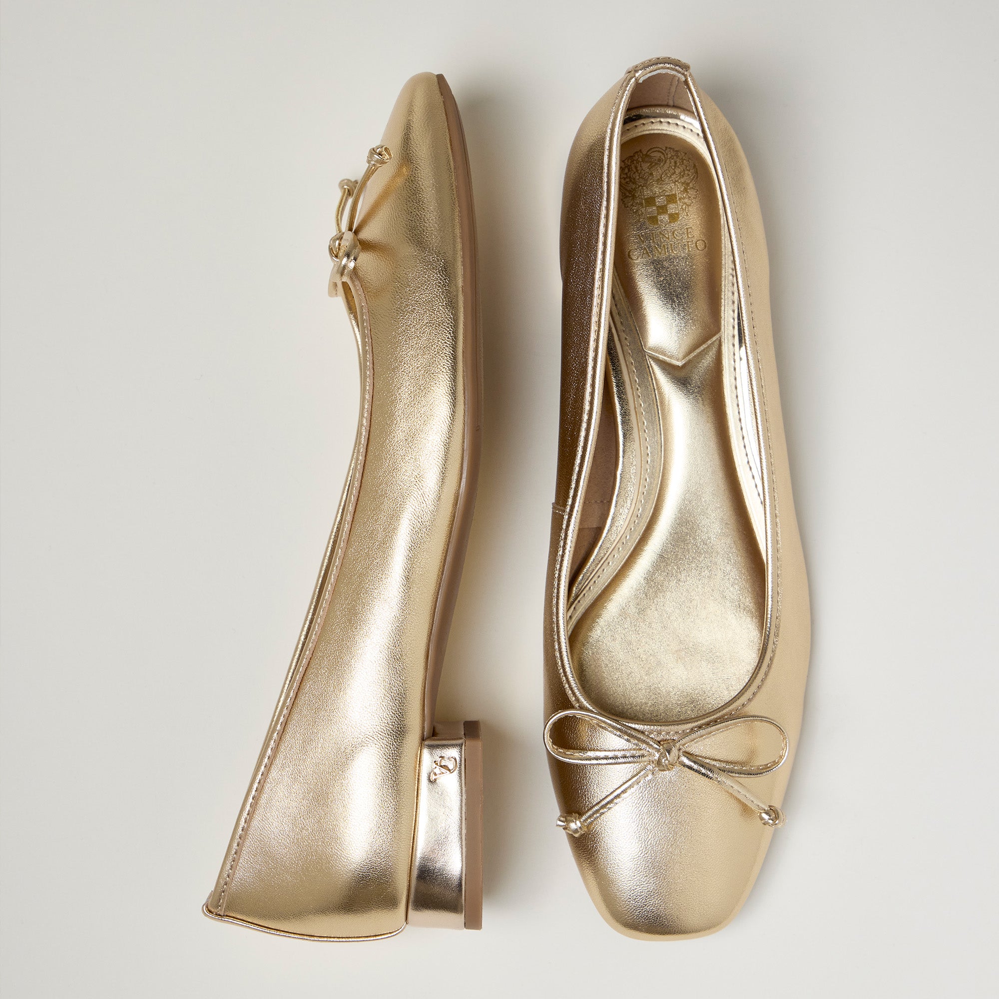 Pair of gold ballet flats on a light gray background