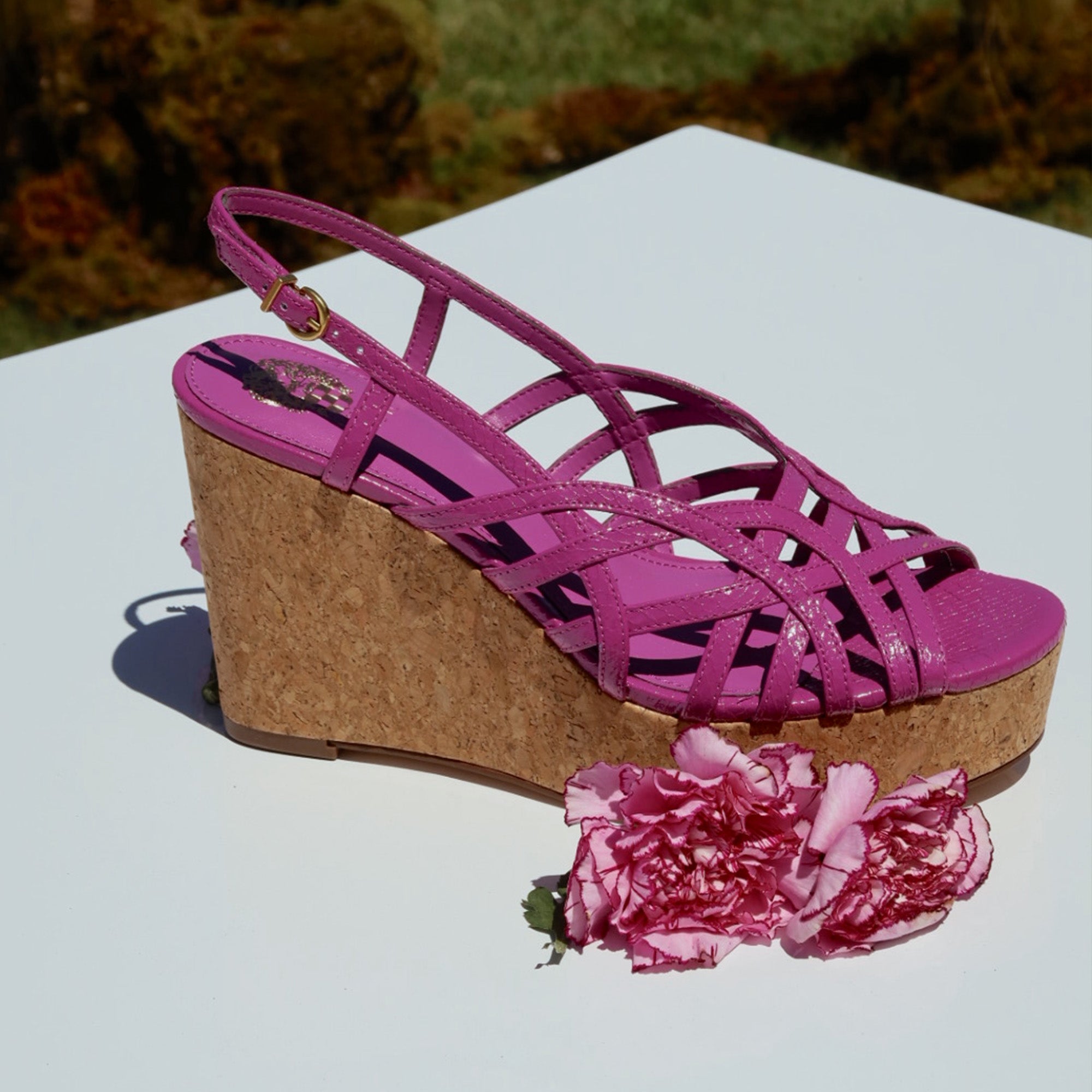 Pink wedge sandal on a white surface with pink flowers.