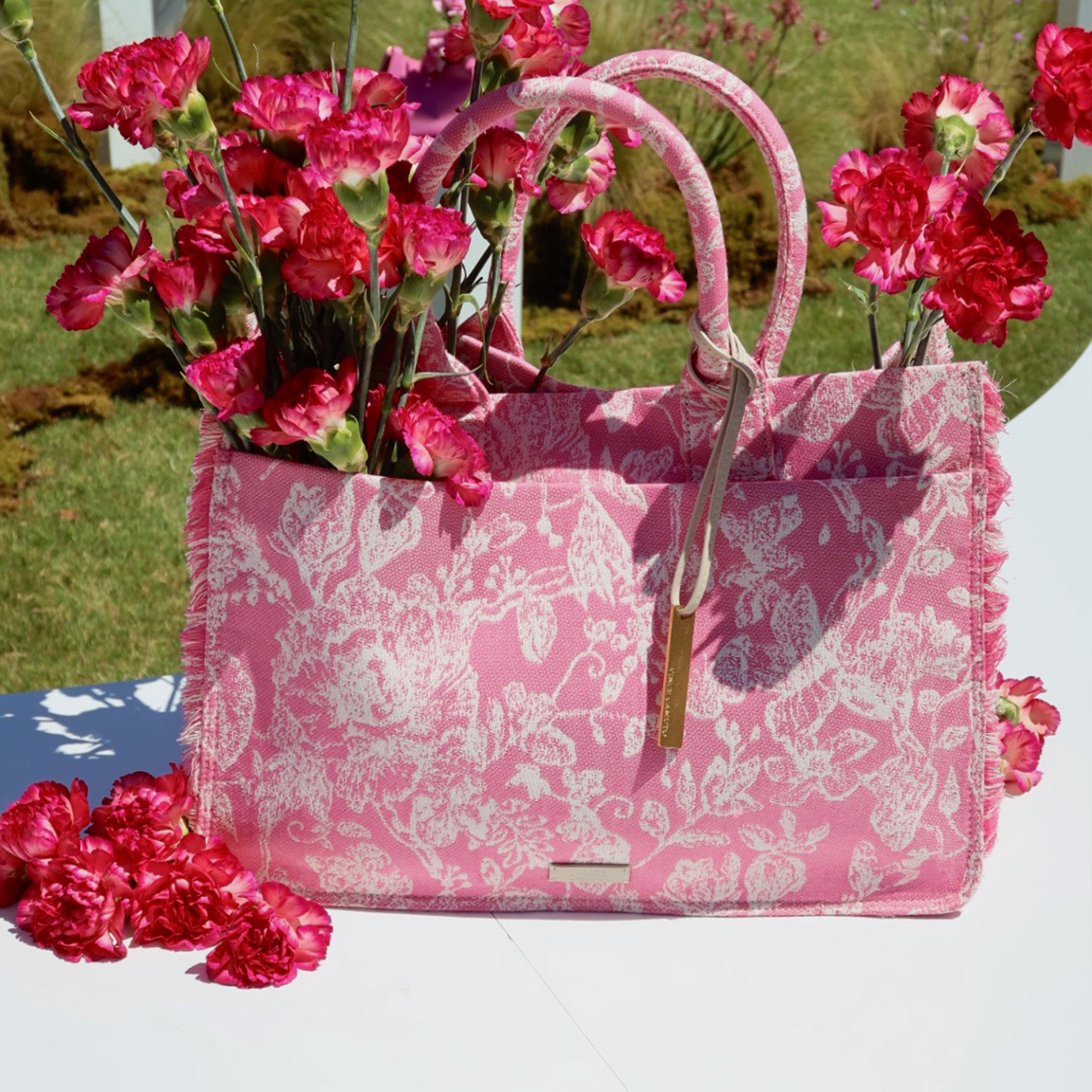 Pink floral-patterned handbag with pink flowers on a white surface