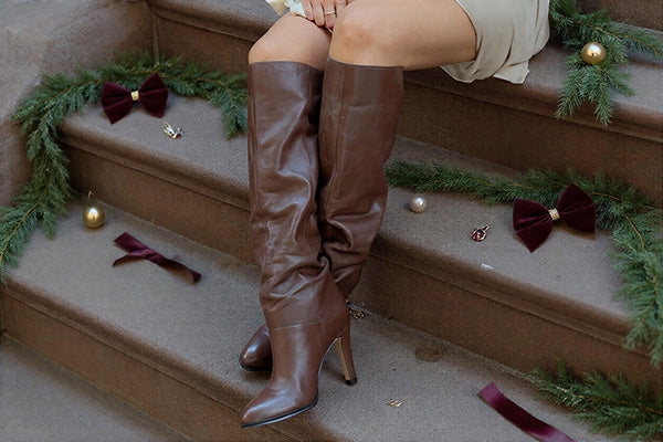 brown knee high boot surrounded by holiday decorations