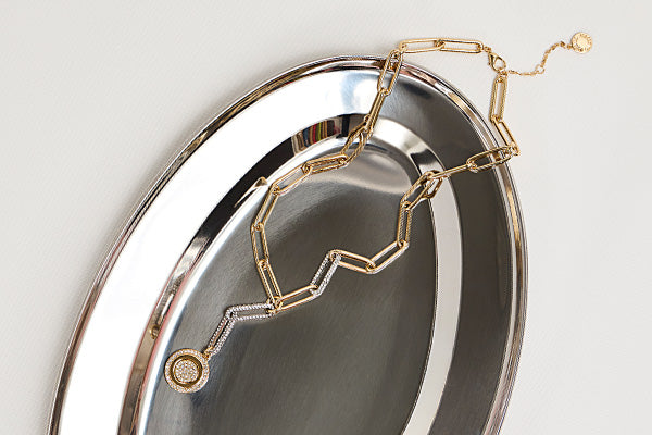gold necklace on silver tray