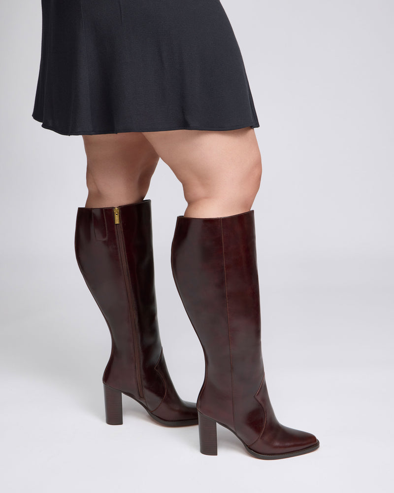 Dark brown Vince Camuto Lecheya Extra Wide Calf Knee High Boots with a leather block heel, worn with a black skirt.