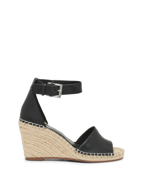 The Vince Camuto Leera Espadrille Wedge Sandal is a black open-toe shoe with an ankle strap and buckle, showcasing a woven espadrille-style platform heel and a brown sole, displayed in side profile.