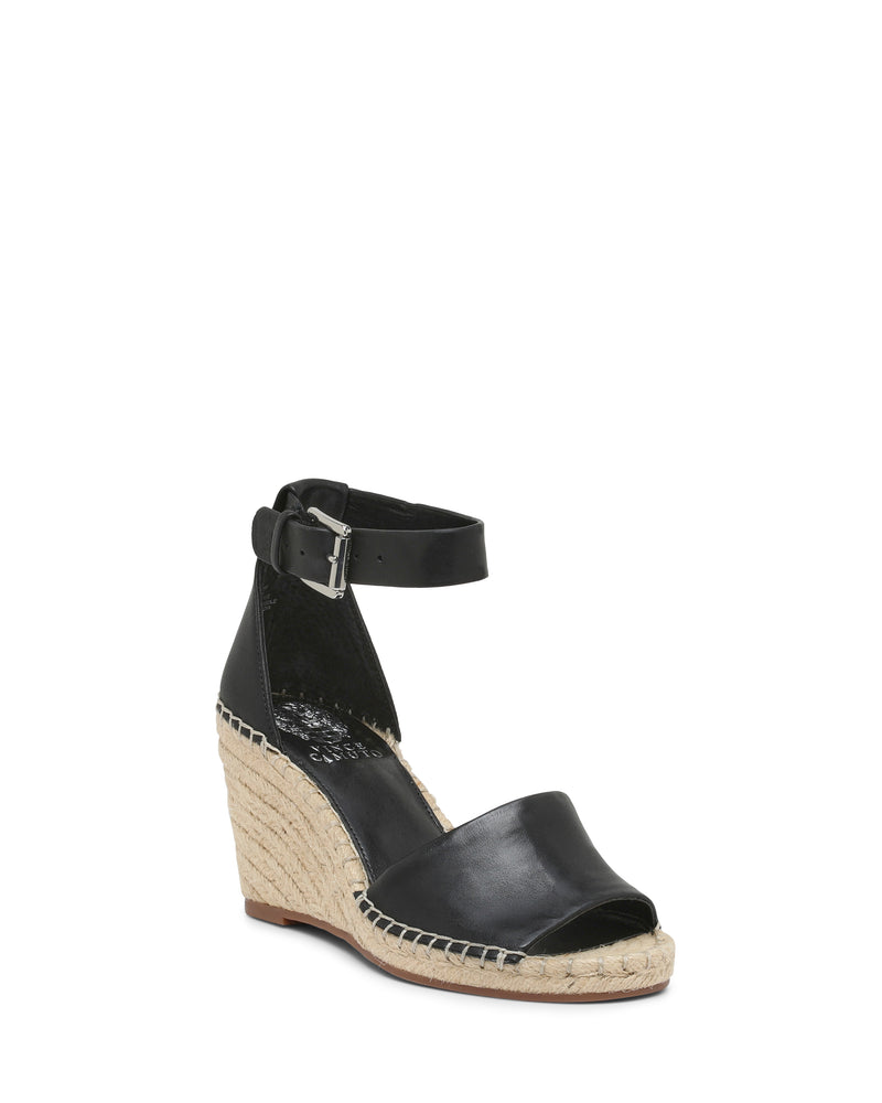 The Leera Espadrille Wedge Sandal by Vince Camuto features a black open-toe design with an ankle strap, silver buckle, and an espadrille-style woven platform heel. It has a black inner footbed, a brown outsole, and offers a stylish yet casual look.
