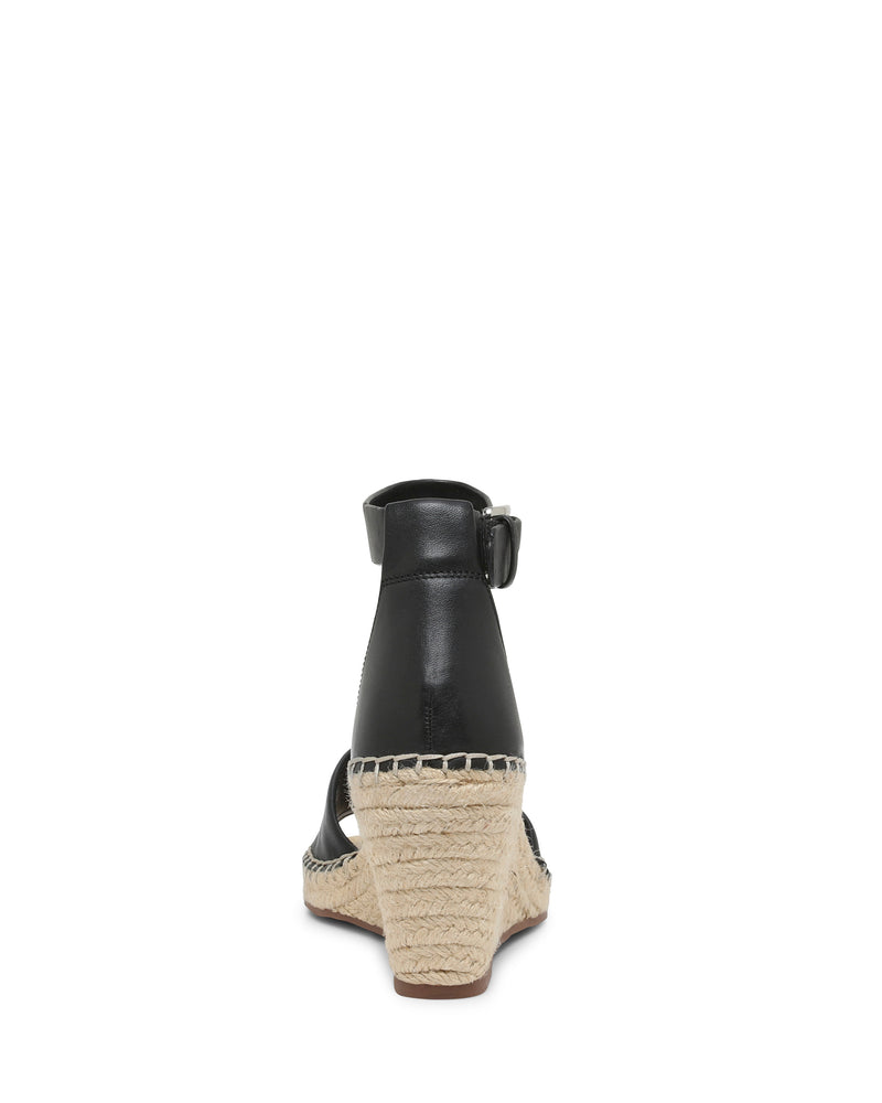 Back view of the Vince Camuto Leera Espadrille Wedge Sandal in black, featuring an ankle strap with a buckle closure and an espadrille-style woven wedge heel, photographed on a plain white background.