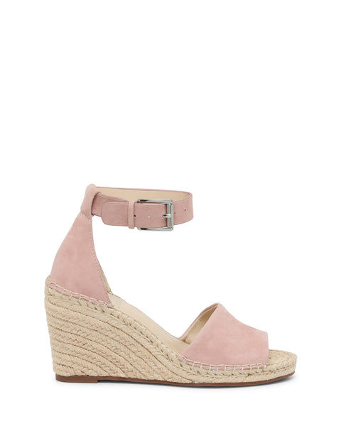 The Vince Camuto Leera Espadrille Wedge Sandal is shown on a white background. This pink suede sandal features an open toe, an ankle strap with buckle, and a woven espadrille-inspired platform wedge heel.