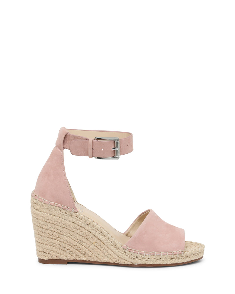 The Vince Camuto Leera Espadrille Wedge Sandal is shown on a white background. This pink suede sandal features an open toe, an ankle strap with buckle, and a woven espadrille-inspired platform wedge heel.