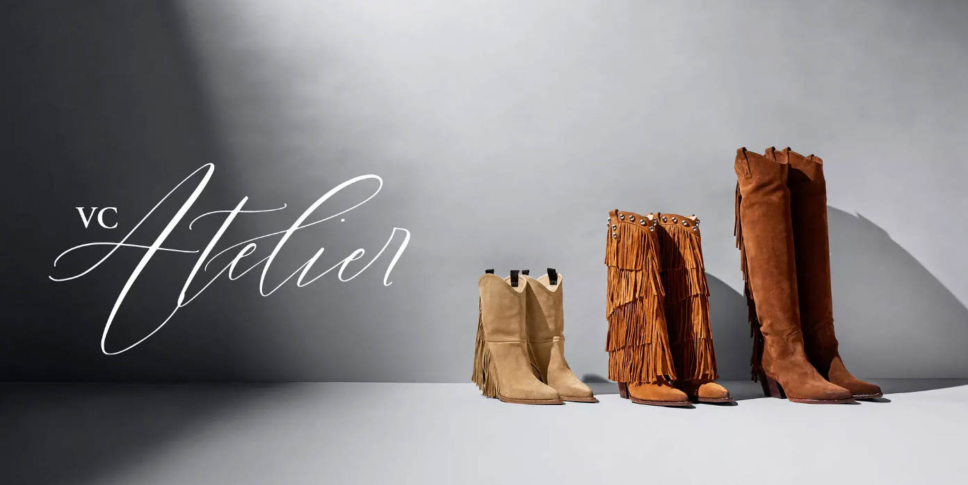 Three pairs of brown cowboy boots, including one fringed pair, are displayed on a gray surface against a gray backdrop. The words VC Atelier appear in elegant script on the left.