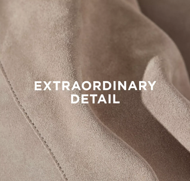 Close-up of beige suede fabric with visible stitching and texture. The words EXTRAORDINARY DETAIL are centered in bold white letters across the fabric.
