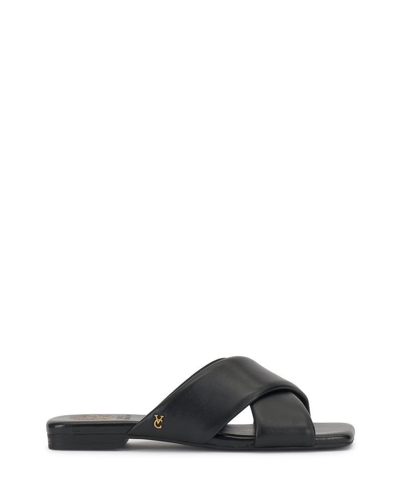 The Vince Camuto Adisey Cross-Band Sandal is a black flat slide with wide crisscross straps and a small gold logo on the side, ideal for daily wear. Shown in side profile on a white background.