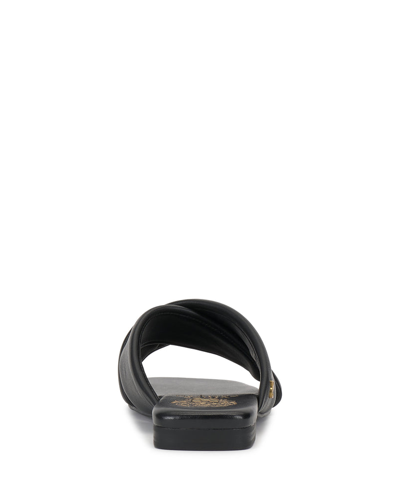 A black Vince Camuto Adisey Cross-Band Sandal is shown from the back on a white background, highlighting its curved strap and gold insole emblem—crafted for comfort and ideal for everyday wear.
