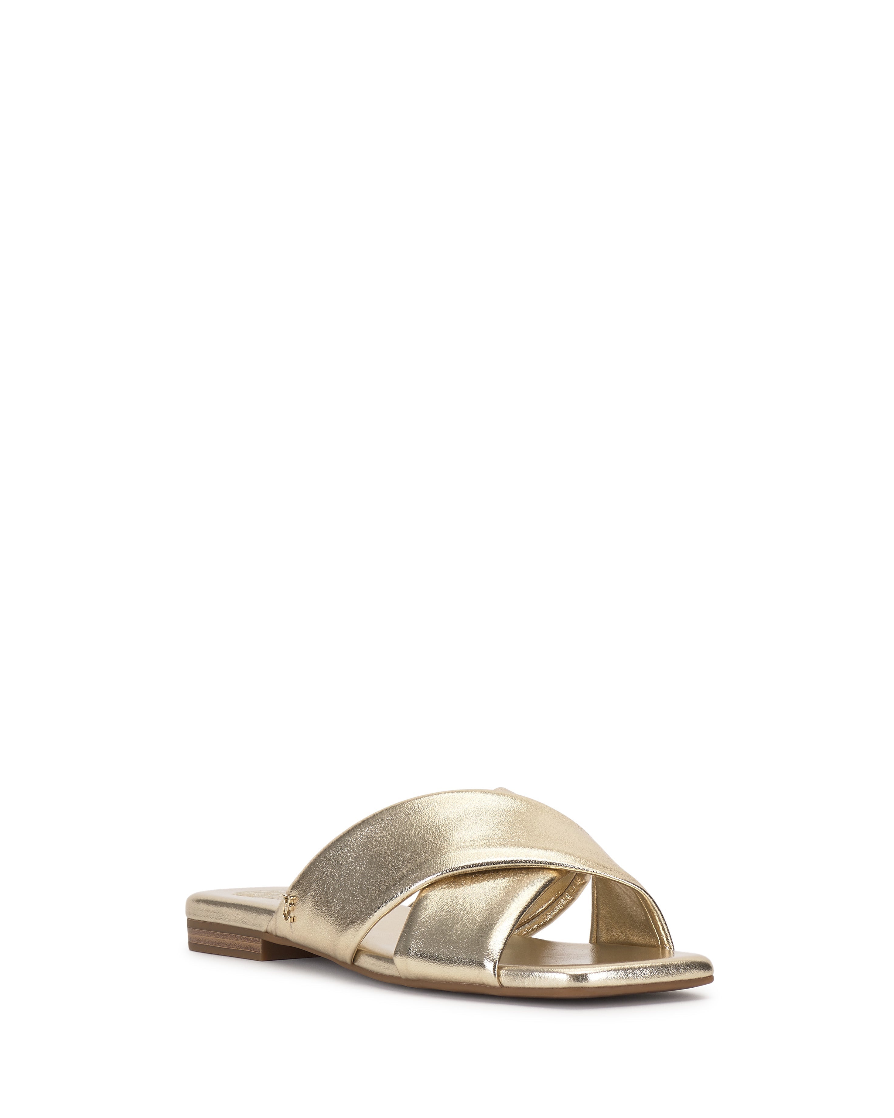 The Vince Camuto Adisey Cross-Band Sandal is a gold metallic flat with crisscross straps and an open toe, shown on a white background—ideal for everyday comfort and style.