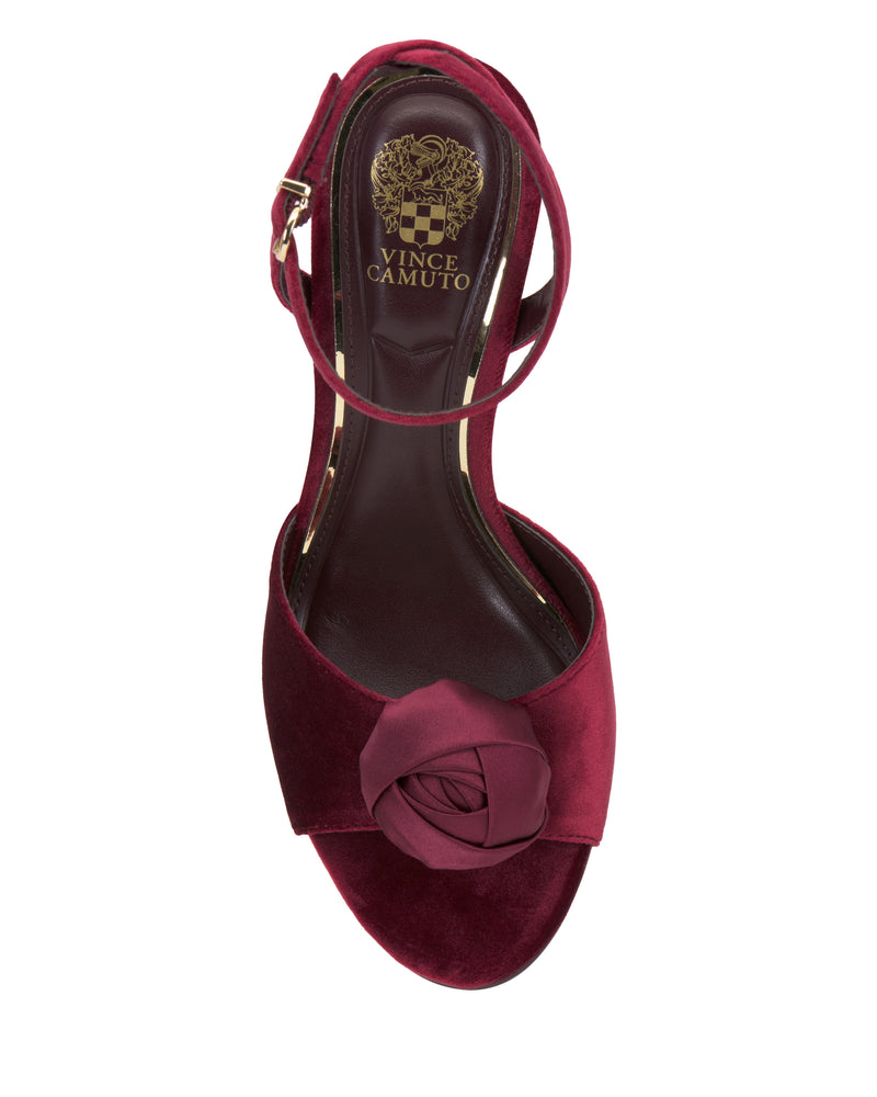 The Aisven Sandal by Vince Camuto is a burgundy high-heel dress sandal with an open toe, ankle strap, and rose-shaped embellishment—ideal for evening events.