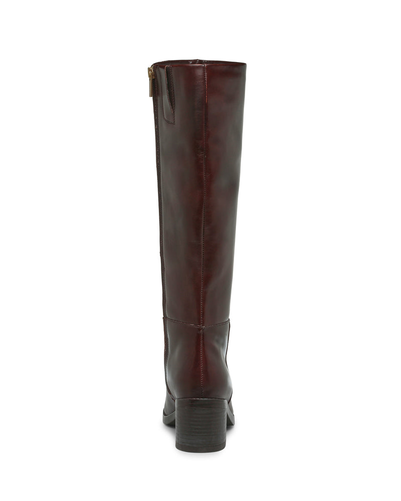 The Vince Camuto Ammar Knee High Boot is pictured from the back, showcasing its tall, dark brown leather design with a low block heel. A zipper and pull tab near the top add practical style, making this boot a versatile addition to any casual wardrobe.