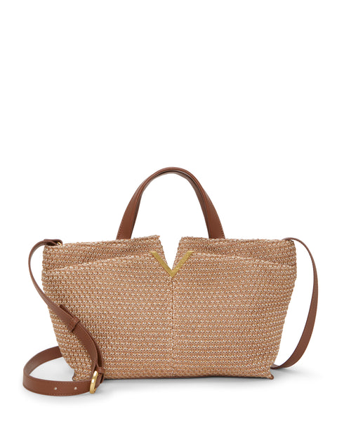 The Vince Camuto April Satchel Bag is a woven straw tote with brown leather handles, a detachable shoulder strap, and a V-shaped gold accent at the top center, shown on a white background.