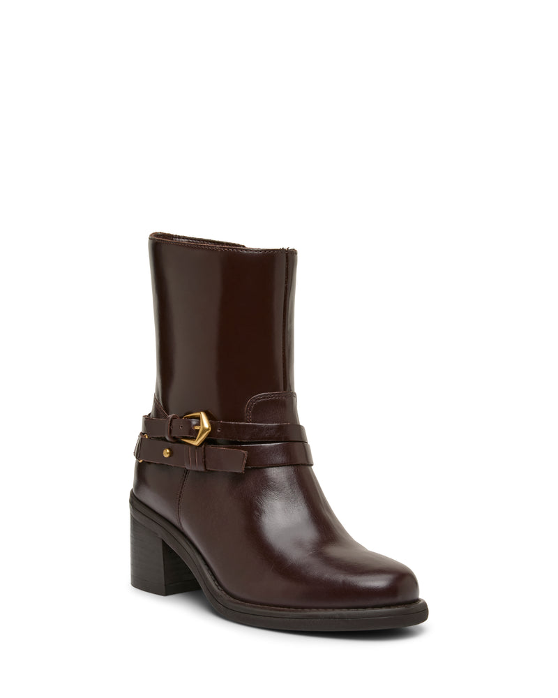 The Vince Camuto Armia Bootie is a dark brown leather bootie with a smooth finish and rounded toe, featuring a block heel, decorative buckle harness strap, and convenient side zipper.