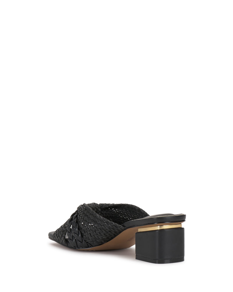 The Atemly Knotted Sandal by Vince Camuto is a black mule with woven details, an open back, and a low block heel with a gold accent near the sole. The shoe is angled to show both side and back views.