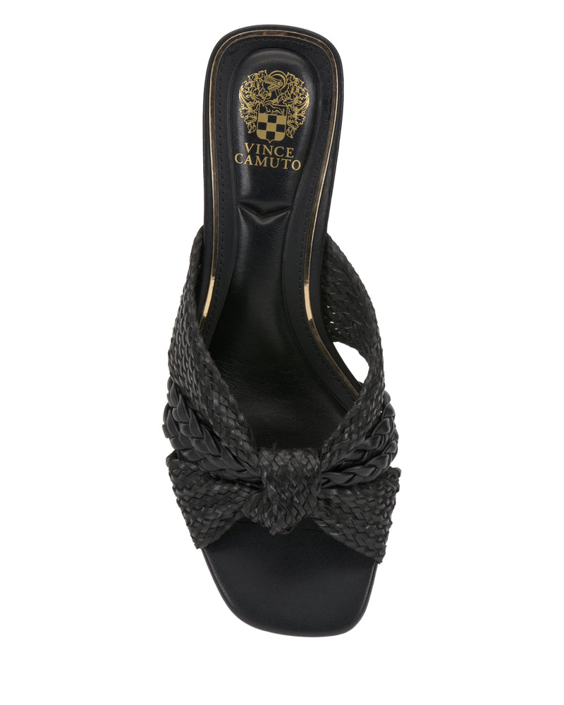 The Vince Camuto Atemly Knotted Sandal is a black bohemian sandal with woven detailing, a wide braided strap, open toe design, and gold Vince Camuto logo on the insole.