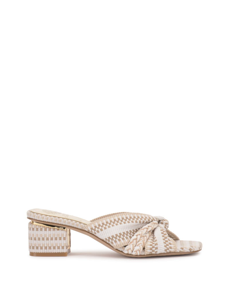 The Vince Camuto Atemly Knotted Sandal is a boho-inspired woven sandal with a low block heel, beige and white pattern, and braided strap detail across the front.