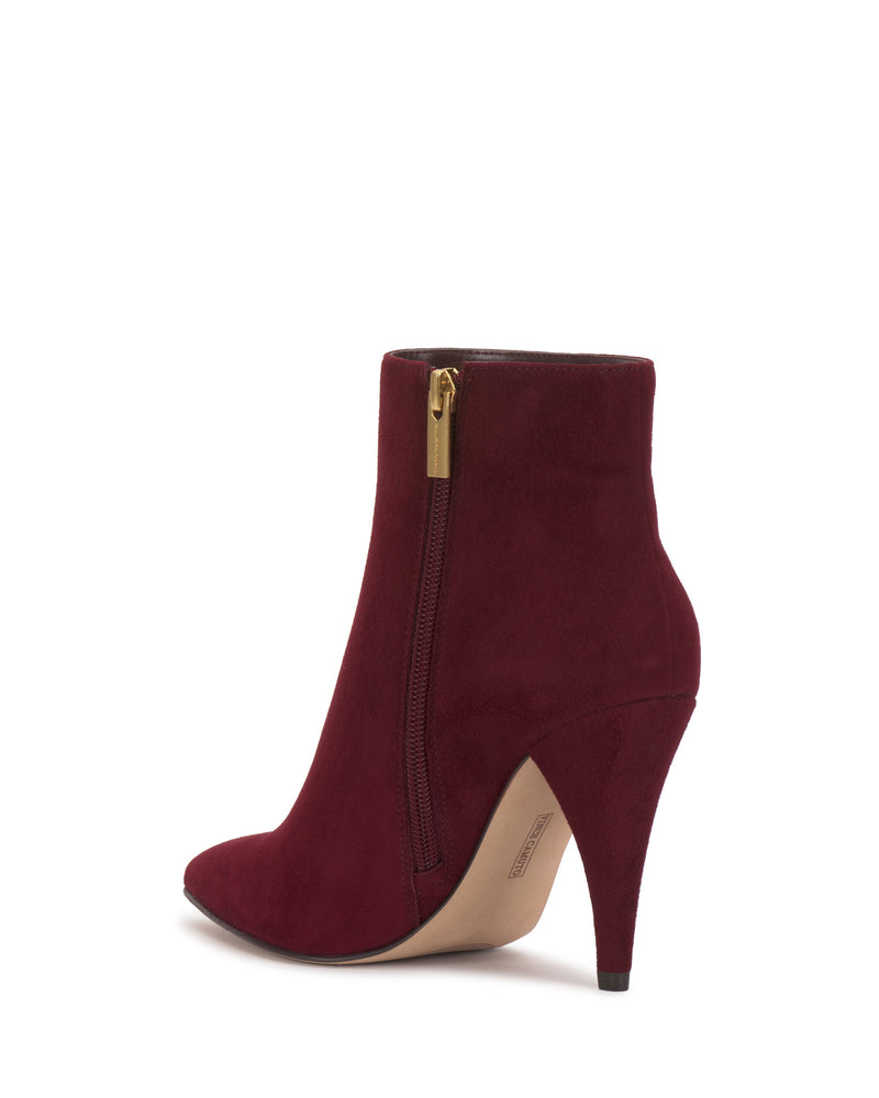 The Attiza Bootie by Vince Camuto is a burgundy suede ankle boot with a pointed toe, gold side zipper, and high stiletto heel, showcased on a plain white background.