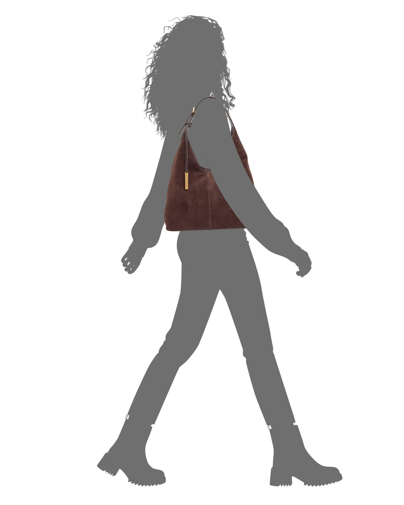A silhouette of a person carrying a sophisticated Vince Camuto Aylla Hobo Bag over their shoulder.