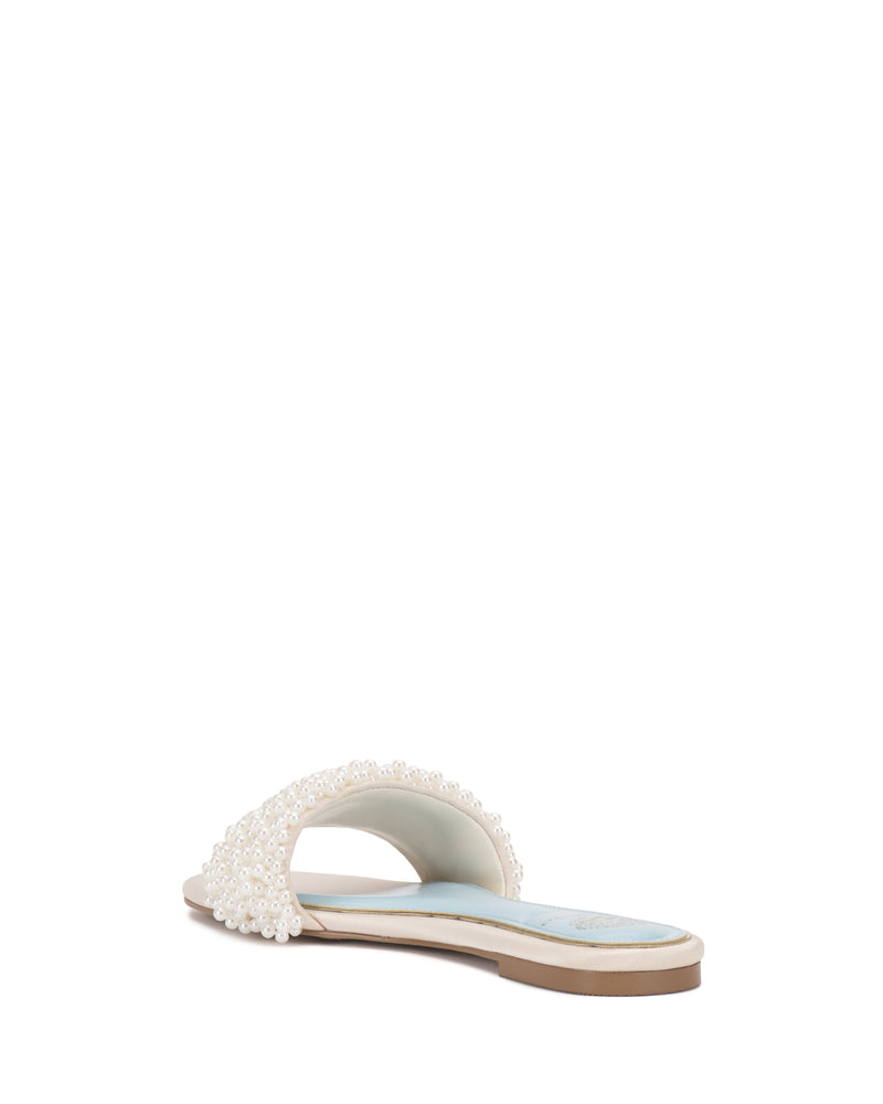 The Balea Beaded Sandal by Vince Camuto features a flat white sole and an open toe band embellished with small pearls and beads, displayed at an angle on a plain white background.
