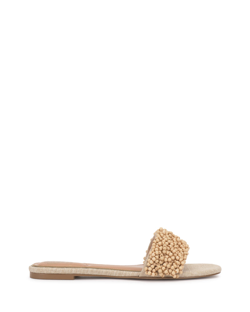 The Balea Beaded Sandal by Vince Camuto features a beige flat design with a wide strap adorned with clustered round beads, beaded accents, a low heel, and a textured sole—versatile for any occasion.