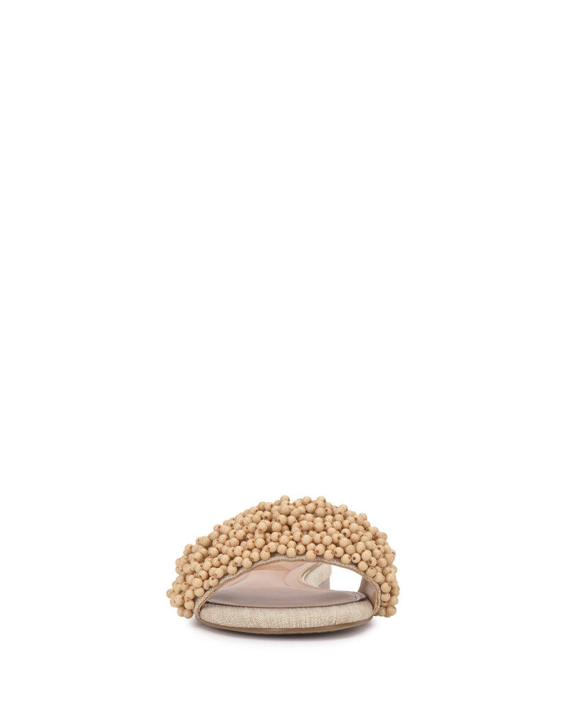 A front view of the Vince Camuto Balea Beaded Sandal, a beige open-toe flat with a textured upper and beaded detailing, displayed against a plain white background.
