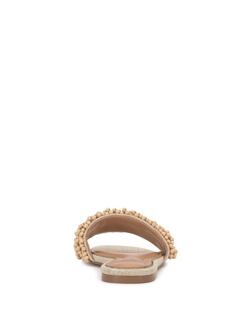The Vince Camuto Balea Beaded Sandal is a beige flat sandal with versatile beaded detailing on a single strap and a lightly textured sole, shown from the back.