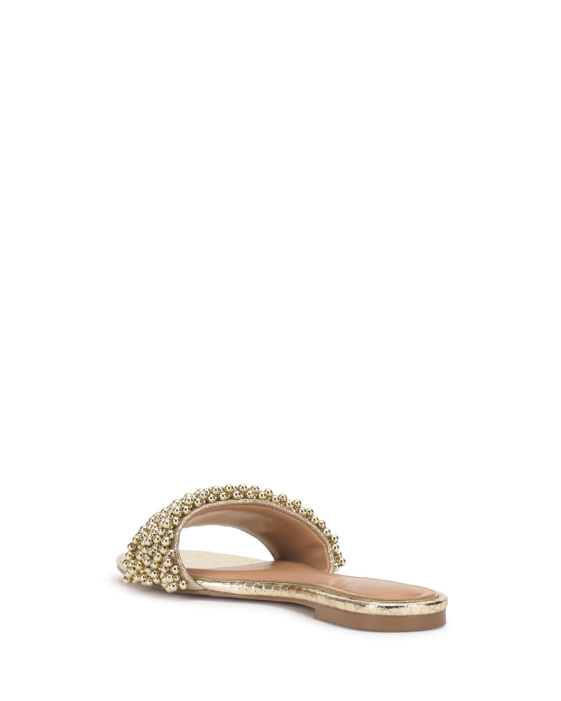 The Balea Beaded Sandal by Vince Camuto is a versatile gold flat with a low heel and wide, beaded strap, shown from the back on a white background.