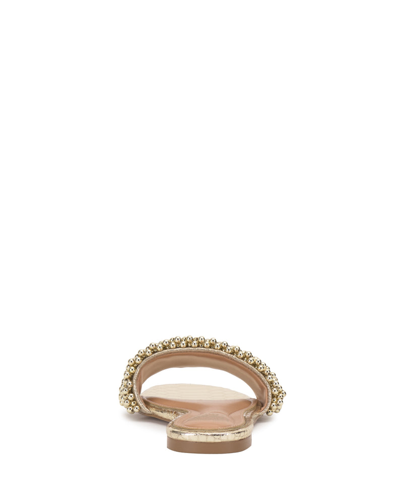The Balea Beaded Sandal by Vince Camuto is shown from the back, featuring a gold metallic sole and a wide strap adorned with elegant beaded detailing, all set against a plain white background.