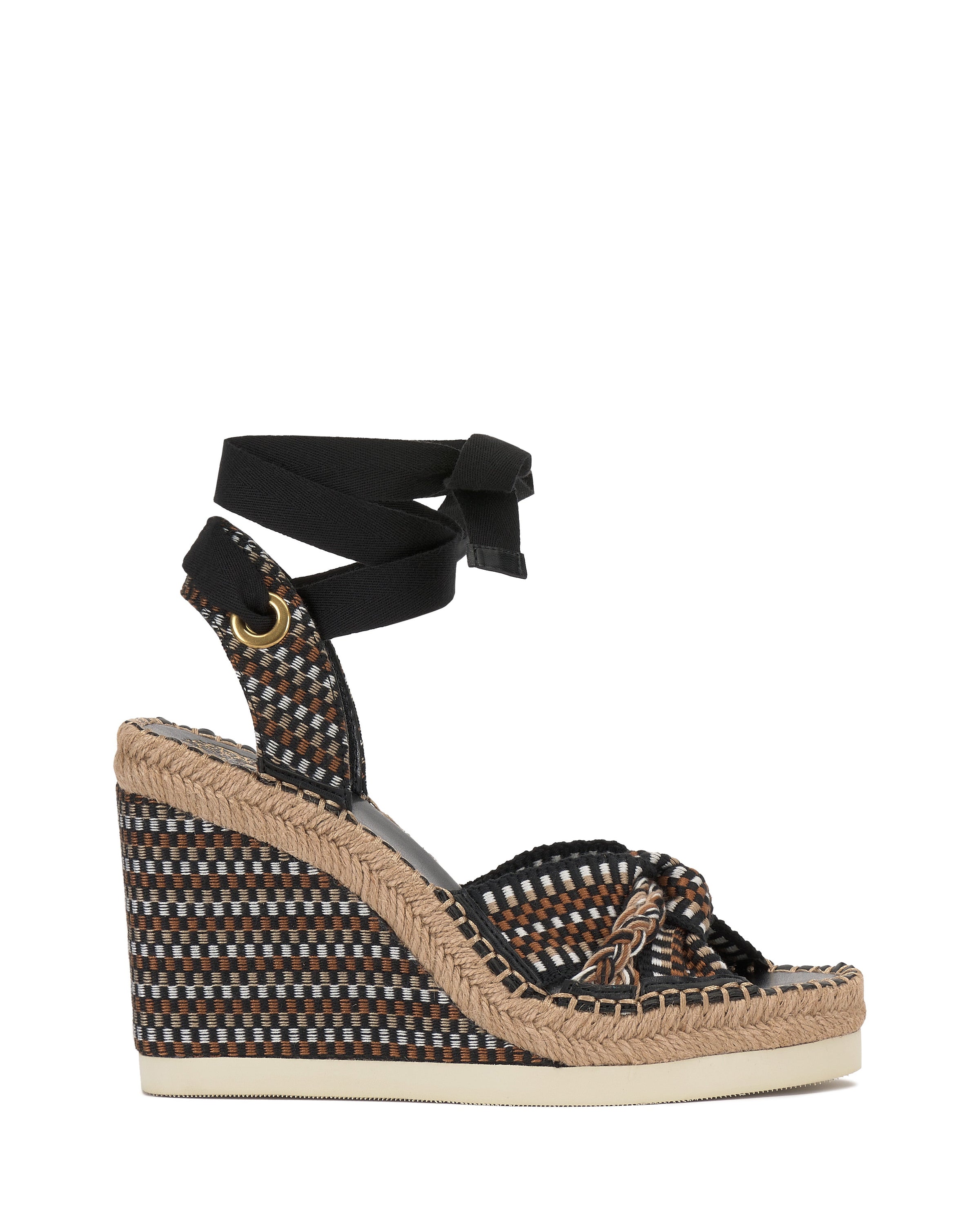 The Bealie Wedge Sandal by Vince Camuto features a woven multicolor design, braided jute espadrille wedge heel, black ankle wrap ties, gold grommet accents, a white sole, and open toe for a chic bohemian look.