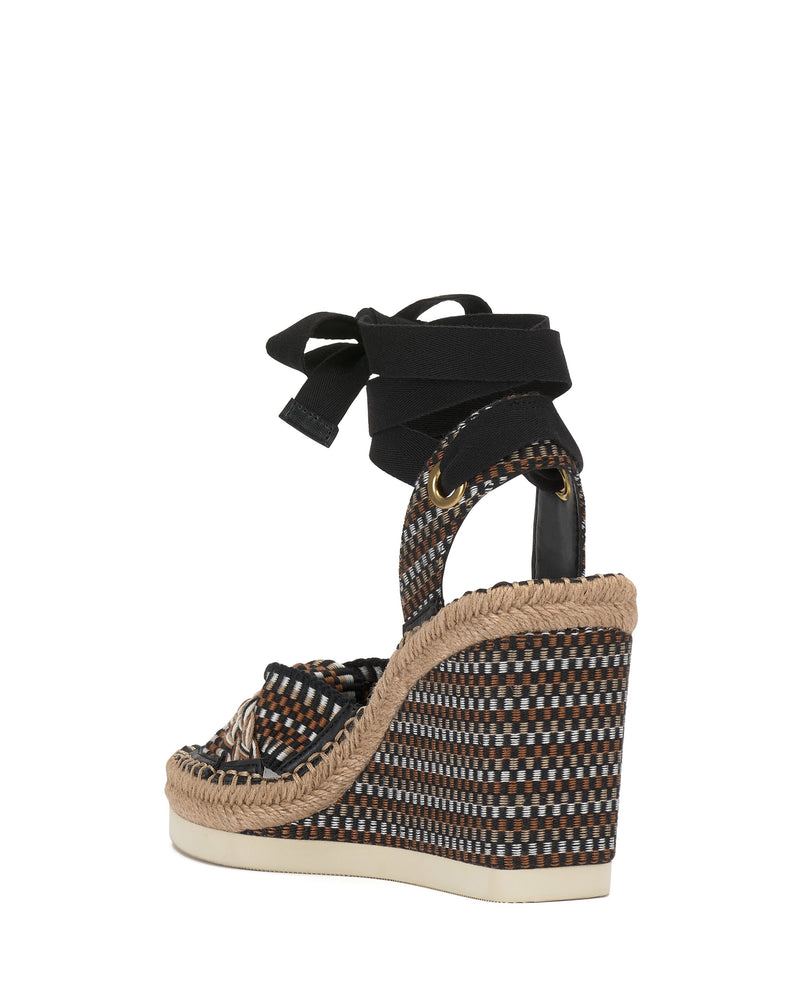 The Vince Camuto Bealie Wedge Sandal features a multicolored checkered pattern, woven ankle ties, black wrap accents, and a jute-trimmed espadrille wedge heel for a chic bohemian look, shown in side view on a white background.