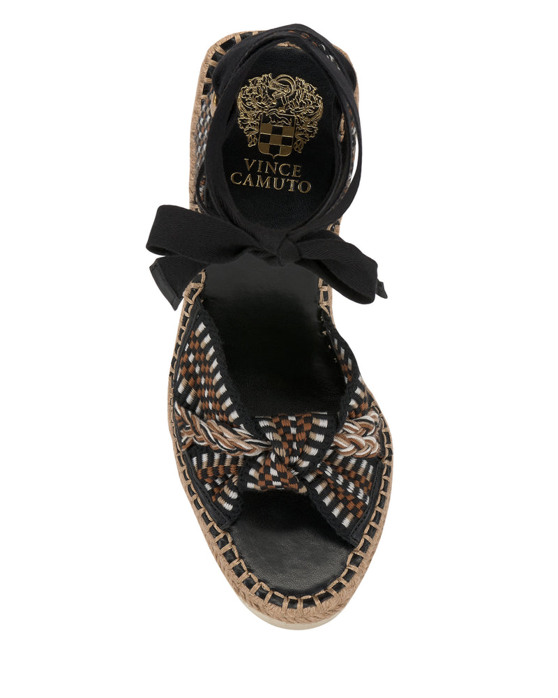 Top view of the Vince Camuto Bealie Wedge Sandal, featuring a woven multicolor pattern, knotted front strap, black insole and ankle tie. The gold brand logo on the heel adds a chic bohemian touch.