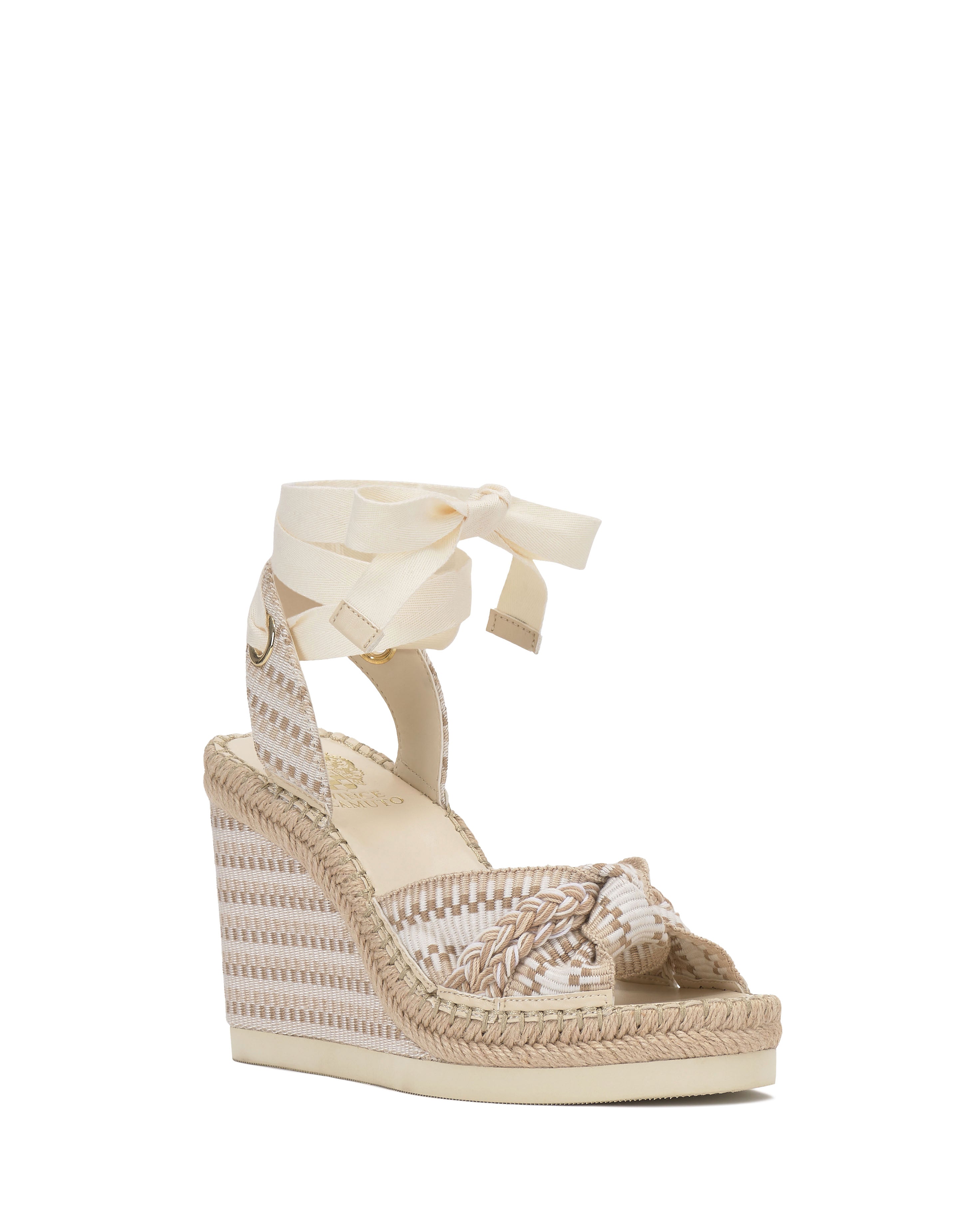The Vince Camuto Bealie Wedge Sandal is a beige and white boho espadrille with woven details, a braided toe strap, ankle tie closure, an espadrille platform, and a high wedge heel.