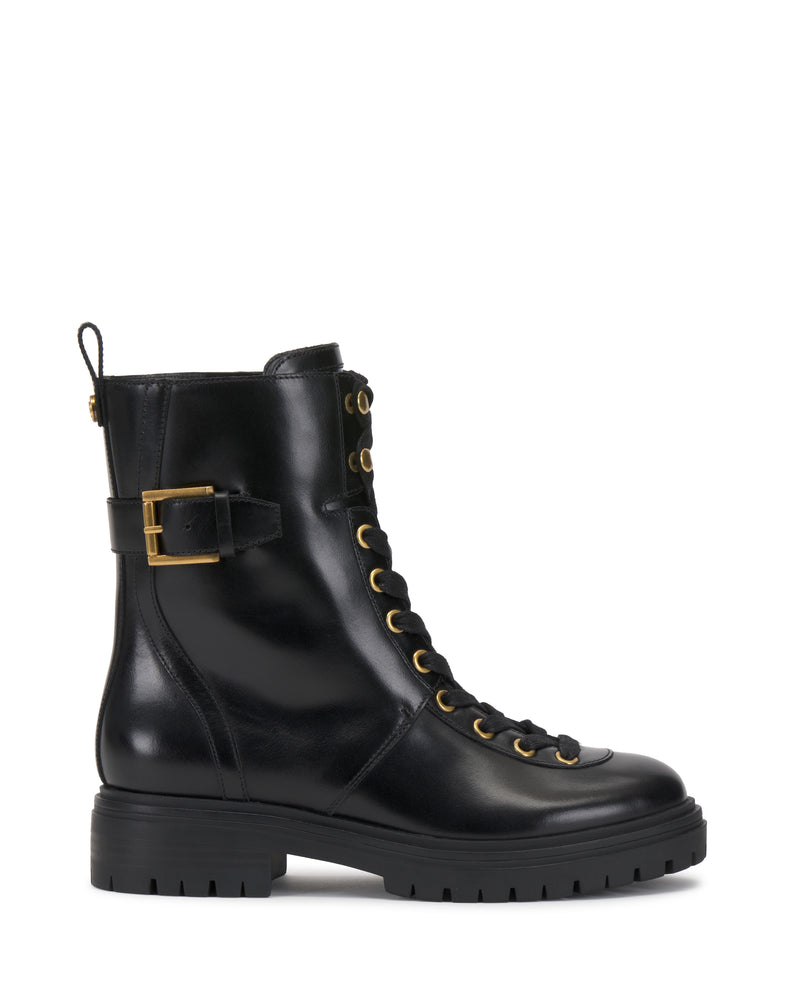 The Becinda Moto Bootie by Vince Camuto is a black leather combat boot featuring gold eyelets, a side buckle detail, a thick treaded rubber sole, a lace-up front, and a rear pull tab, shown in side profile on a white background.