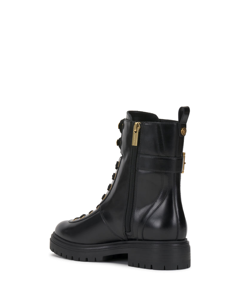The Becinda Moto Bootie by Vince Camuto is a black leather lace-up boot featuring gold eyelets, a side zipper, a thick treaded sole, and a buckle detail near the top. It is shown at a slight angle from the back.