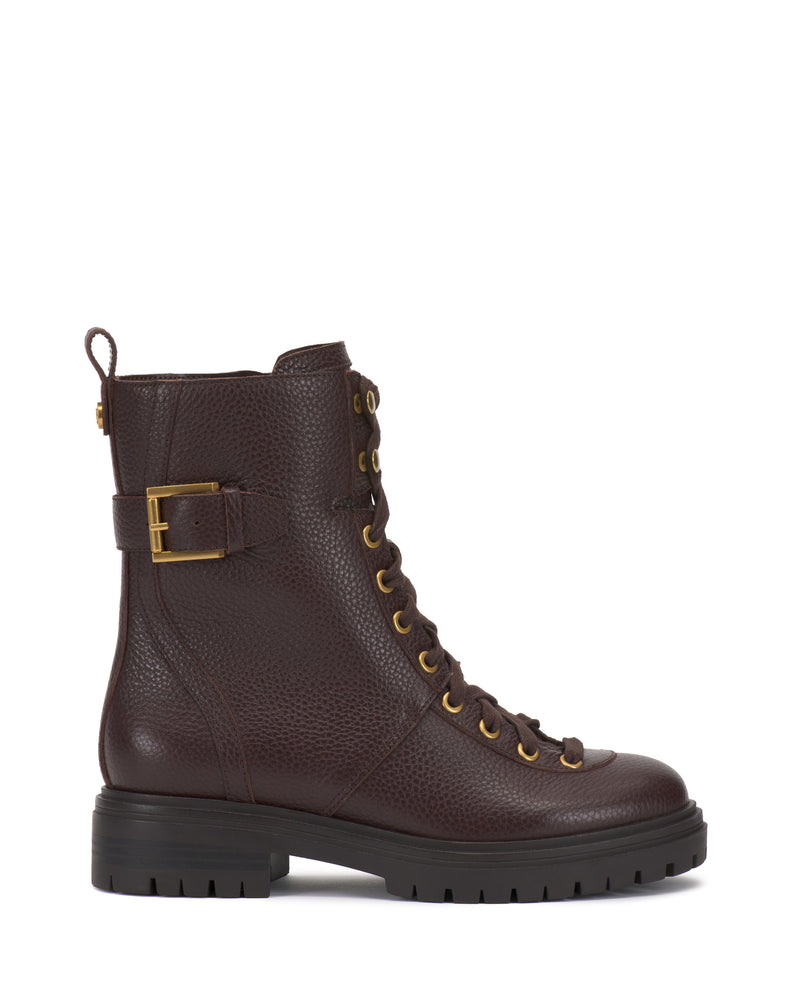 The Vince Camuto Becinda Moto Bootie is a dark brown leather lace-up combat boot featuring gold eyelets, side buckle detail, a pull tab at the back, and a black chunky rubber sole. The boot is displayed from the side against a white background.