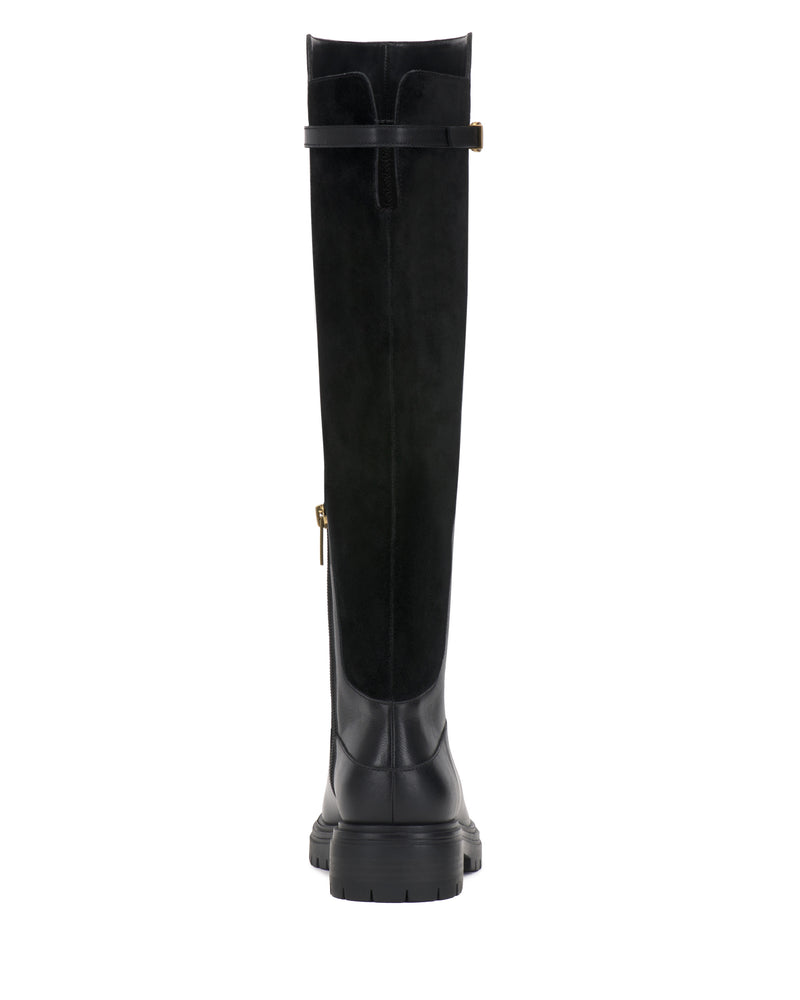 The Vince Camuto Bertla Knee High Riding Boot is a tall black leather boot shown from the back, highlighting a decorative strap with a small gold buckle near the top and a textured rubber sole.