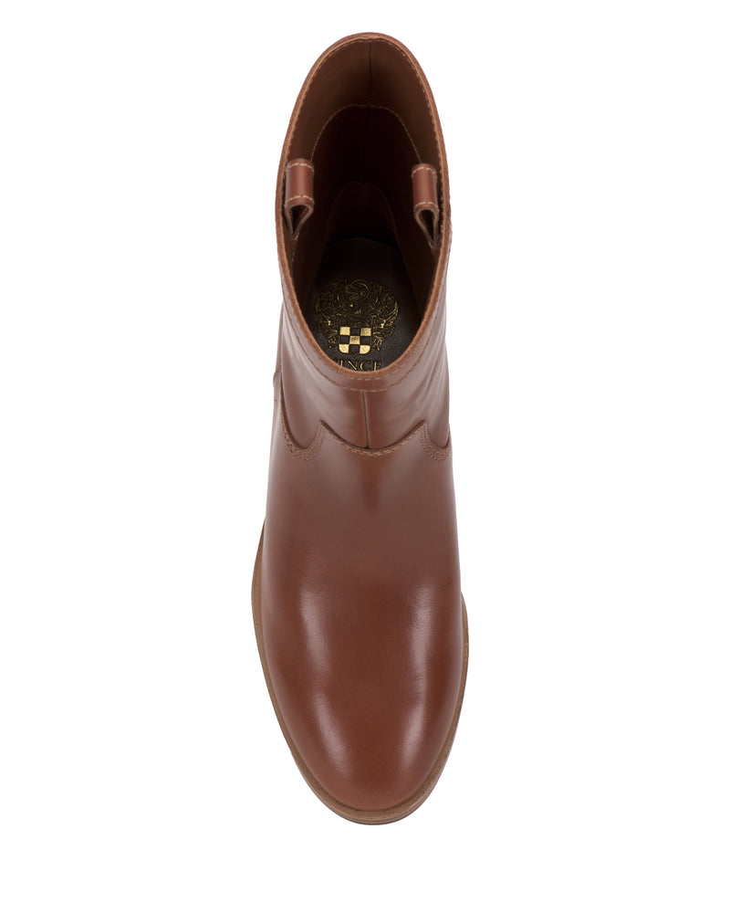 A top view of the Vince Camuto Bezzley Bootie—a single brown leather ankle boot with a round toe and pull tabs on the sides—displays a gold Vince Camuto emblem on the insole.