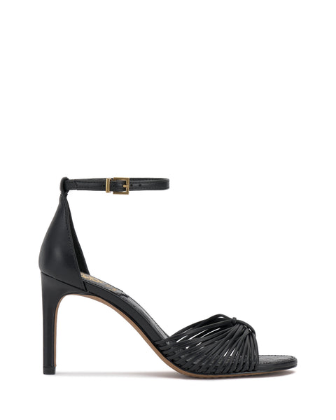 The Blaine Sandal by Vince Camuto is a black ankle strap sandal featuring a tall heel, slender buckle, closed heel, open toe, and woven straps across the front.
