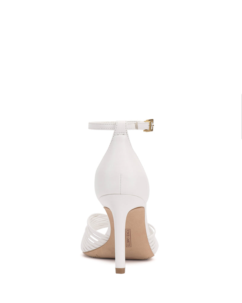 The Vince Camuto Blaine Sandal is a white strappy high heel, shown from the back with a thin ankle strap, gold buckle, and tall slim heel, displayed against a plain white background.