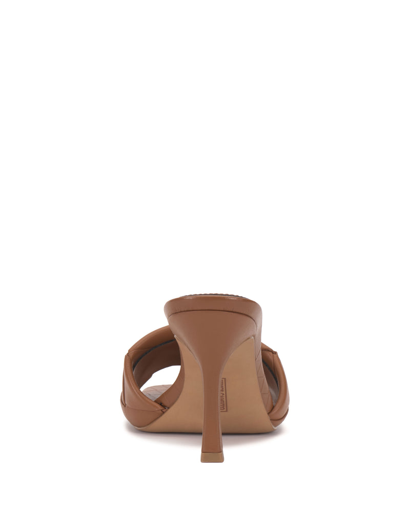 The Vince Camuto Brelanie Woven Mule is a brown high-heeled sandal with braided straps and a single stiletto heel, shown from the back on a plain white background.