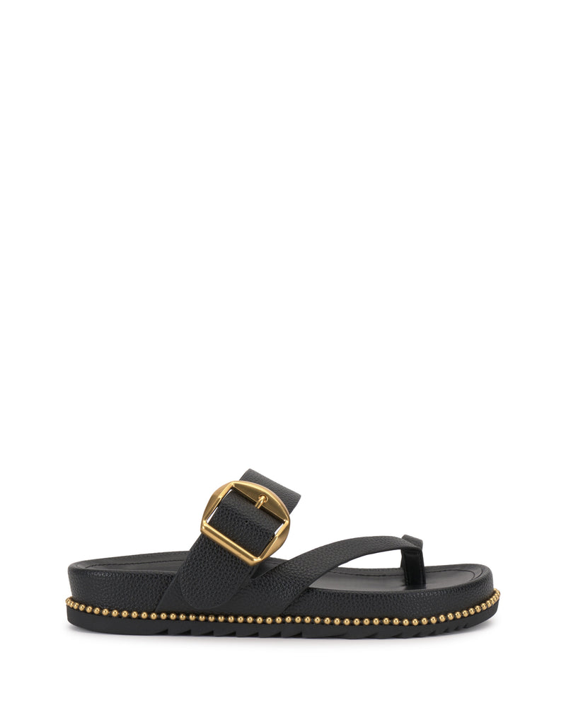 The Camilo Slide by Vince Camuto is a black thong sandal with a wide buckle strap featuring a large gold buckle. Its flat, contoured sole is decorated with small gold studs along the edge for added style and comfort.