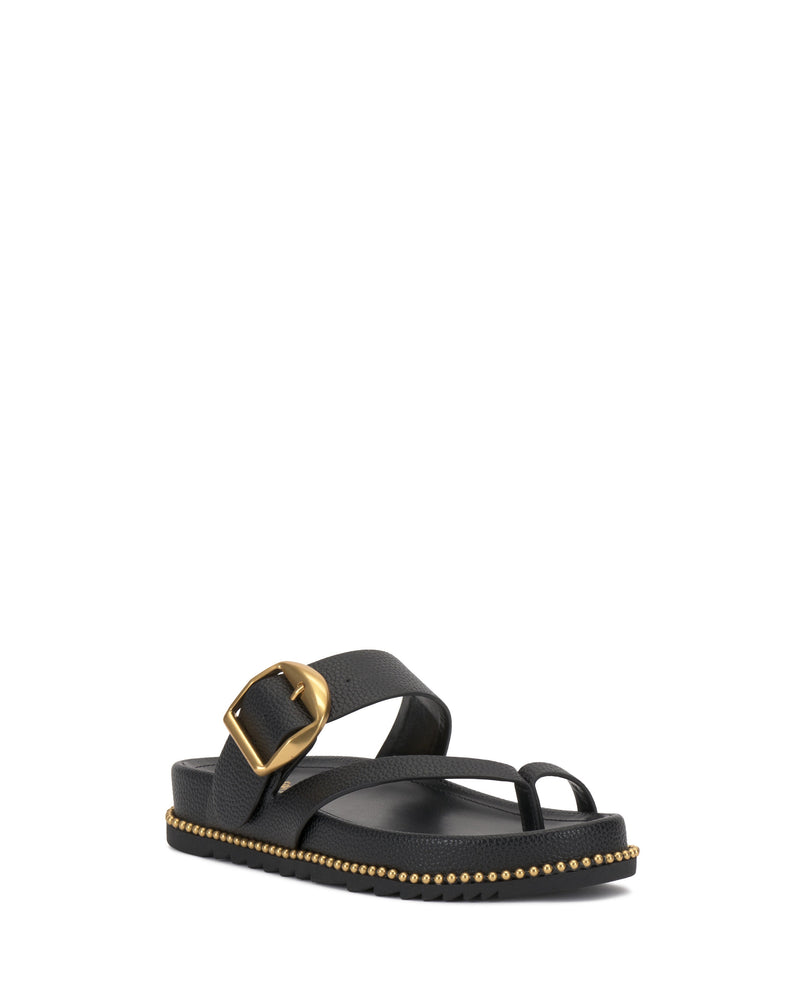 The Vince Camuto Camilo Slide is a black sandal featuring a wide strap with a large gold buckle, toe loop, small gold studs outlining the flat textured sole, and a contoured footbed for extra comfort.